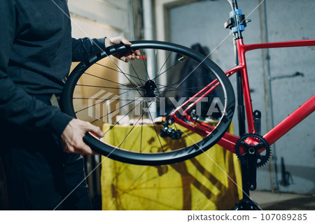 Mechanic repairman assembling wheel custom bicycle in workshop Mechanic repairman assembling wheel custom bicycle in workshop 107089285