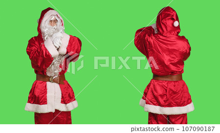 Impatient santa claus in suit checking time on wristwatch while he stands over greenscreen backdrop. Young adult dressed in festive winter character costume waiting for something, xmas spirit. 107090187