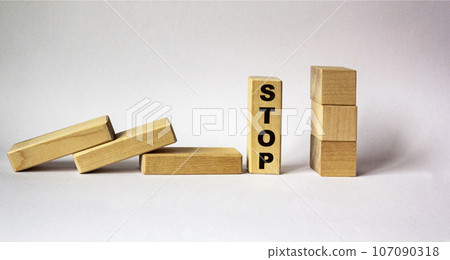 Concept of hand stop falling wooden blocks on a white background. On the block the word STOP. 107090318