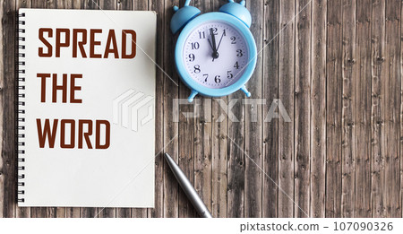 Spread the word, text on notepad and wooden background. Business concept 107090326