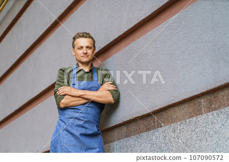 Service man, waiter or chef, in portrait against backdrop of restaurant building. Hospitality and professionalism of service industry. Expertise and dedication to culinary art. High quality photo 107090572