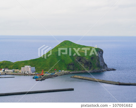 Cape Peshi with its white lighthouse seen from the cycling road that goes around Rishiri Island in the Sea of Japan in the southwest direction from Wakkanai City, Hokkaido 107091682