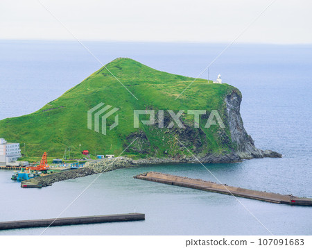 Cape Peshi with its white lighthouse seen from the cycling road that goes around Rishiri Island in the Sea of Japan in the southwest direction from Wakkanai City, Hokkaido 107091683