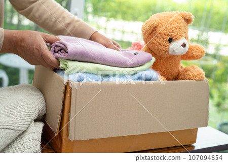 Donation box with used clothes and doll at home to support help for poor people in the world. Donation box with used clothes and doll at home to support help for poor people in the world. 107094854
