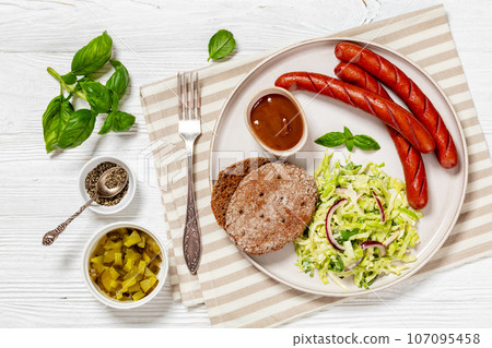 sausages with coleslaw salad, bbq sauce on plate 107095458