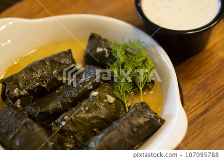 plate of delicious stuffed grape leaves with parsley garnish. 107095788
