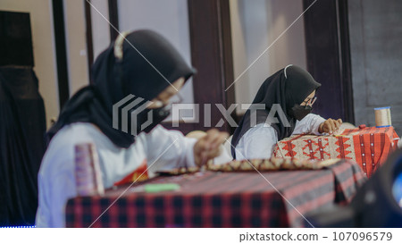woman is weaving cloth, or so-called traditional tapis cloth, typical of Lampung province, by hand 107096579