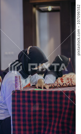 woman is weaving cloth, or so-called traditional tapis cloth, typical of Lampung province, by hand 107096582