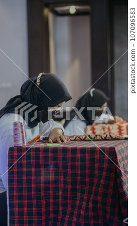 woman is weaving cloth, or so-called traditional tapis cloth, typical of Lampung province, by hand 107096583