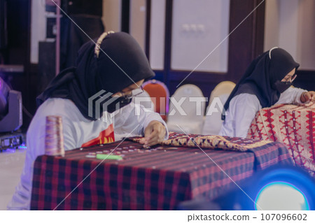 woman is weaving cloth, or so-called traditional tapis cloth, typical of Lampung province, by hand 107096602