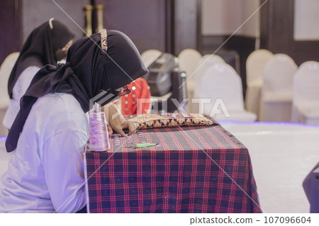 woman is weaving cloth, or so-called traditional tapis cloth, typical of Lampung province, by hand 107096604