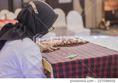 woman is weaving cloth, or so-called traditional tapis cloth, typical of Lampung province, by hand 107096608