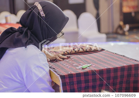 woman is weaving cloth, or so-called traditional tapis cloth, typical of Lampung province, by hand 107096609