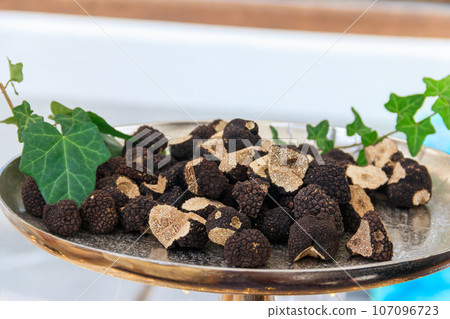 Expensive black truffles gourmet mushrooms on the plate on a table 107096723