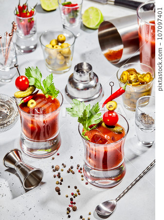 Glasses of bloody mary vodka and tomato juice mix with cocktail utensils on light background 107097401