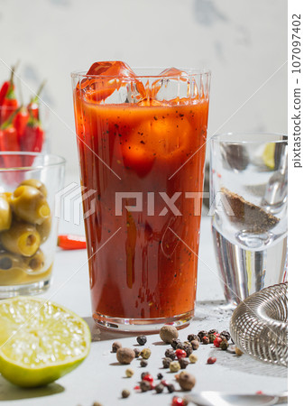 Cocktail bloody mary with pepper,lime,bar shaker and strainer on light board.Macro 107097402