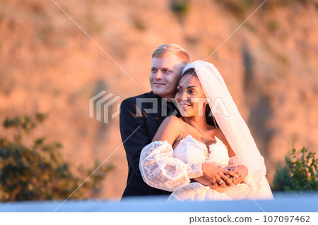 Happy newlyweds in the rays of the setting sun Happy newlyweds in the rays of the setting sun 107097462