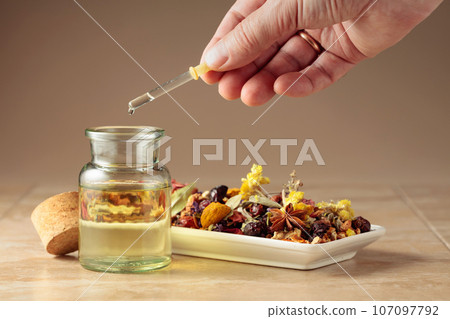 Dropping essential oil or herbal tincture into a glass bottle. Dropping essential oil or herbal tincture into a glass bottle. 107097792