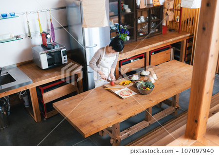一位 50 多歲的女士在廚房做飯 107097940