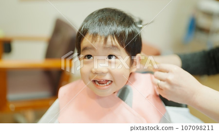 A 3-year-old boy getting a haircut at a beauty salon A 3-year-old boy getting a haircut at a beauty salon 107098211