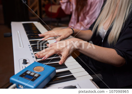 Closeup of female hands on an electronic piano. A laptop on a keyboard instrument. 107098965