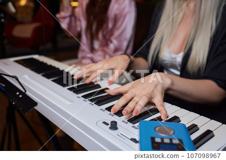 Closeup of female hands on an electronic piano. A laptop on a keyboard instrument. 107098967