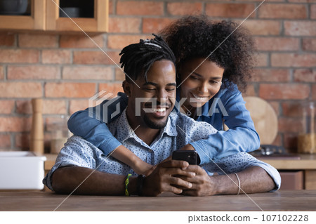 Happy African American couple using smartphone in kitchen together 107102228
