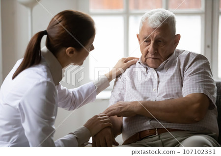 Caring woman doctor comfort senior male patient 107102331