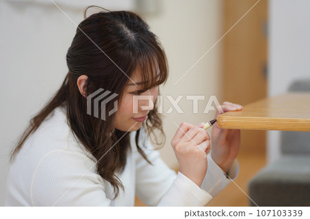 一個女人在桌子上的划痕上使用疤痕面具 107103339