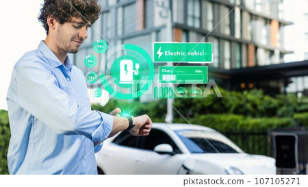 Businessman checking EV car battery status in hologram from smartwactch. Peruse Businessman checking EV car battery status in hologram from smartwactch. Peruse 107105271