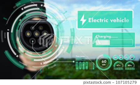 EV charger pointing in front of camera with blurry wind turbine farm. Peruse EV charger pointing in front of camera with blurry wind turbine farm. Peruse 107105279