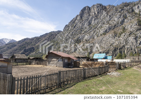 A village with wooden houses in a valley at the foot of the mountains in Altai Mountains in spring 107105394