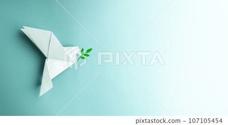 Peace and New Beginnings oPeace and New Beginnings of Hope. A white dove Flying over the Blue background Holds an Olive Branch. World International Peace Day. The Concept of a Fluttering Bird that 107105454