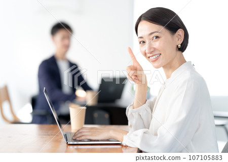 A woman pointing while operating a computer A woman pointing while operating a computer 107105883