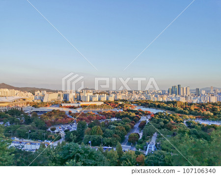 Colourful foliage trees in Autumn with various buildings and World Cup Stadium in the afternoon and blue sky. 107106340