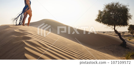 Woman in sands dunes of desert at sunset 107109572