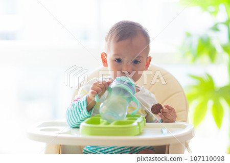 Baby eating solid foods in high chair. Baby eating solid foods in high chair. 107110098
