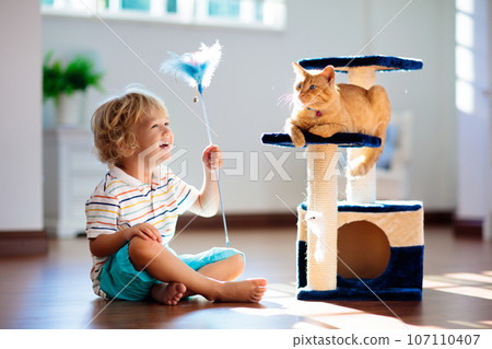 Child playing with cat at home. Kids and pets. 107110407