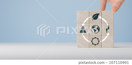 Circular economy concept, recycle, environment, reuse, manufacturing, waste, consumer, resource. Hand put wooden cubes with icons of circular economy on blue background. Sustainable development 107110991