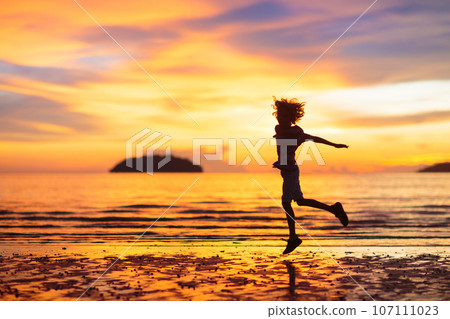 Child playing on ocean beach. Kid at sunset sea. Child playing on ocean beach. Kid at sunset sea. 107111023