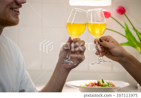 Happy romantic couple celebrating with glasses of wine in kitchen at home. 107111975
