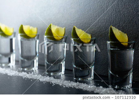 Tequila with lime and sea salt on a black table. 107112310