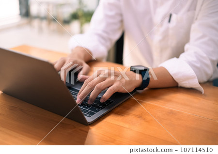 Young businessman hands typing on laptop computer, checking email or searching online information 107114510
