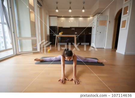Young athletic attractive woman practicing yoga doing exercises. Works out at home or in a yoga studio, sportswear, blue pants and a full-length top indoors. Healthy lifestyle concept. 107114636