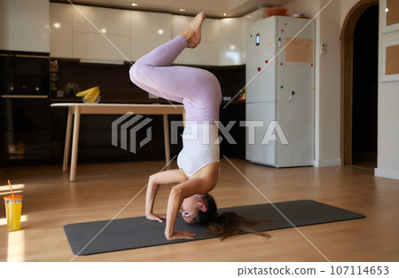 Beautiful young woman practicing yoga at home. Beautiful young woman practicing yoga at home. 107114653