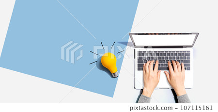 Person using a laptop computer and a light bulb 107115161