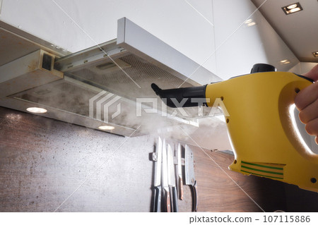 house cleaning. Girl brushes steam cleaners kitchen drawing with steam in green gloves. cleaning of a surface. house cleaning. Girl brushes steam cleaners kitchen drawing with steam in green gloves. cleaning of a surface. 107115886
