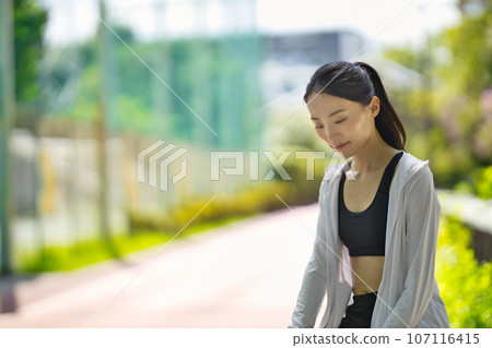 一位穿著運動服的年輕女子站在綠樹叢中的肖像 一位穿著運動服的年輕女子站在綠樹叢中的肖像 107116415