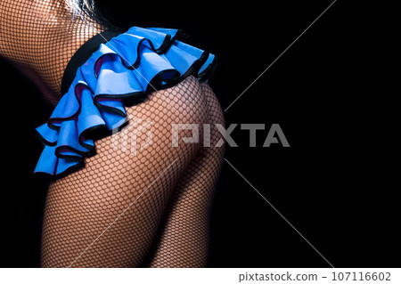 Female sexy figure legs in mesh tights and blue skirt and beautiful butt on dark background 107116602