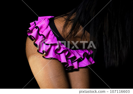 Female sexy figure legs in mesh tights and pink skirt on dark background Female sexy figure legs in mesh tights and pink skirt on dark background 107116603